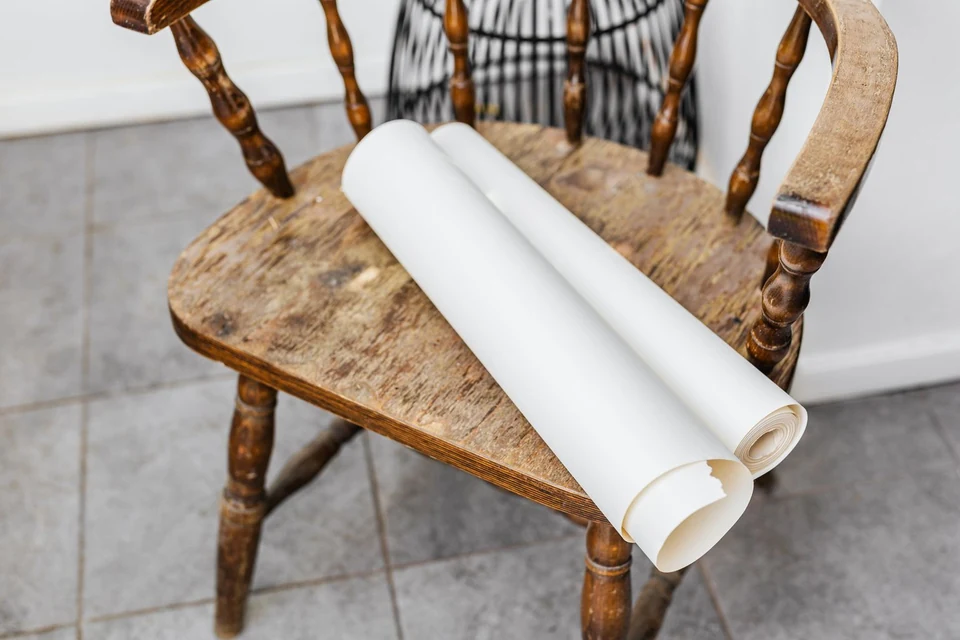 Rouleaux de papier peint posés sur une chaise en bois
